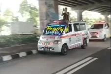 Pria Duduk di Atas Mobil...