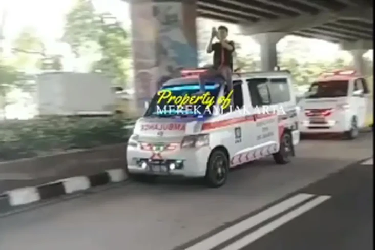 Pria Duduk di Atas Mobil...
